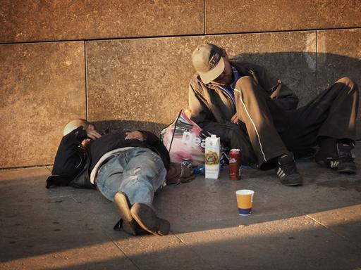 Zwei Obdachlose liegen auf einem Fußweg an einer Hauptstraße im Bezirk Mitte in Berlin am 04.10.2014.