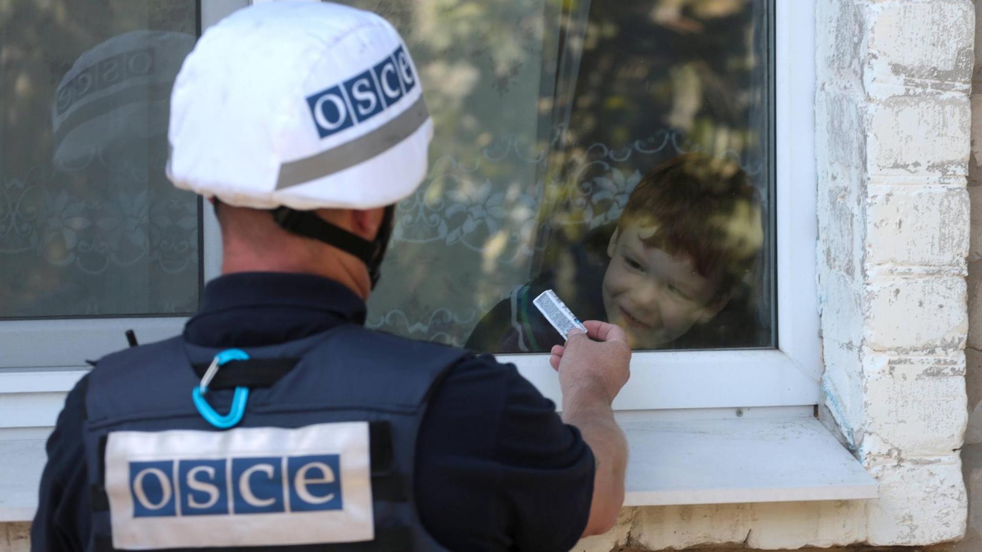Ein Mitarbeiter der OSZE-Beobachtermission in der Ukraine interagiert mit einem Jungen in einem Dorf in der Region Donezk. Ein Mitarbeiter der OSZE-Beobachtermission in der Ukraine interagiert mit einem Jungen in einem Dorf in der Region Donezk.