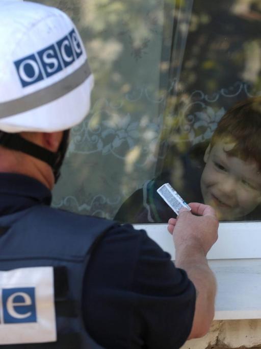 Ein Mitarbeiter der OSZE-Beobachtermission in der Ukraine interagiert mit einem Jungen in einem Dorf in der Region Donezk.