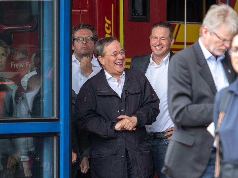 Armin Laschet (2. v.l., CDU), Ministerpräsident von Nordrhein-Westfalen, lacht während Bundespräsident Steinmeier (nicht im Bild) im Hochwassergebiet in Erftstadt ein Pressestatement gibt.