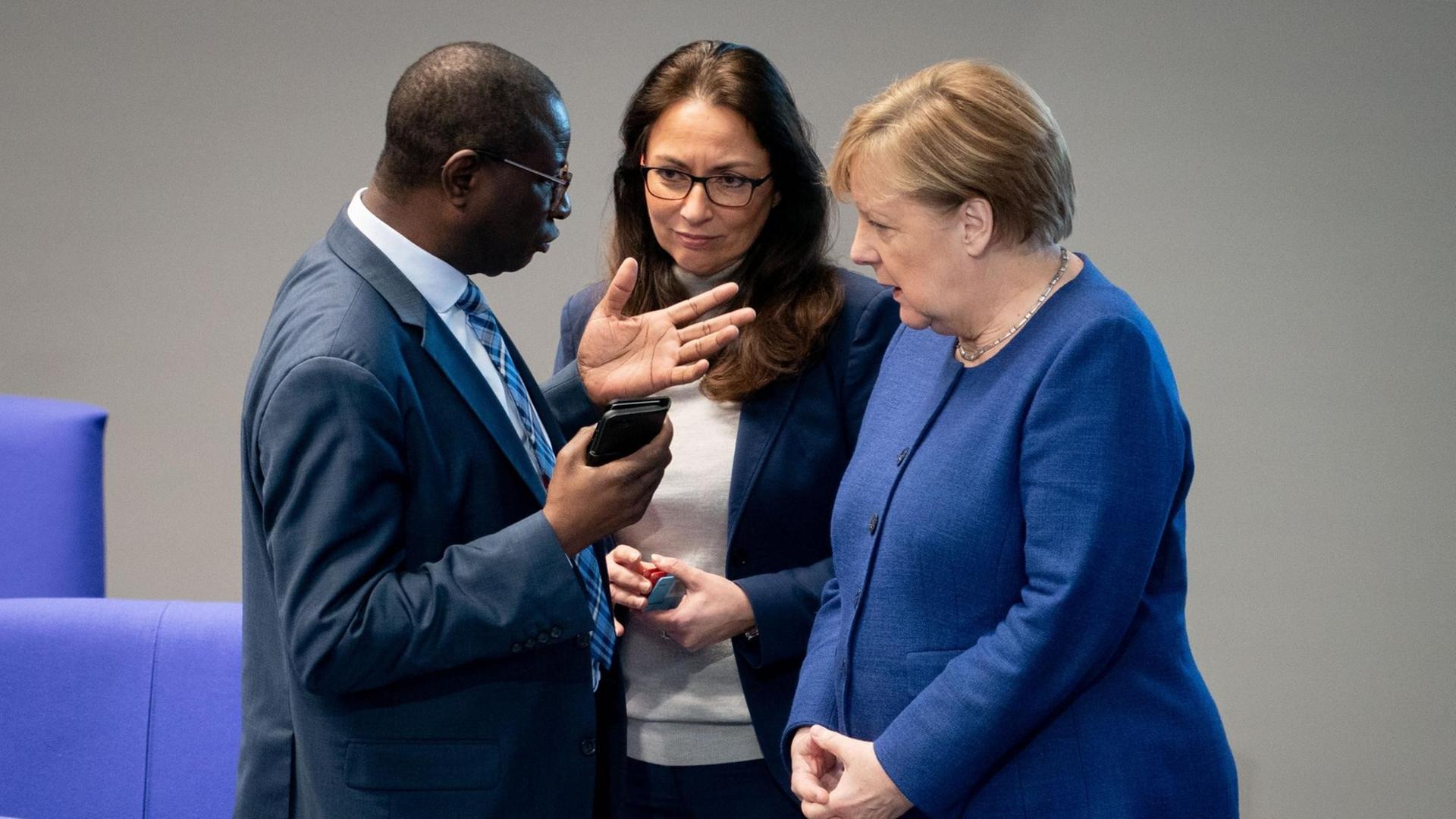 Die Bundeskanzlerin Angela Merkel unterhält sich bei der Sitzung des Bundestages mit den SPD-Bundestagsabgeordneten Karamba Diaby und Yasmin Fahimi. Die Bundeskanzlerin Angela Merkel unterhält sich bei der Sitzung des Bundestages mit den SPD-Bundestagsabgeordneten Karamba Diaby und Yasmin Fahimi.