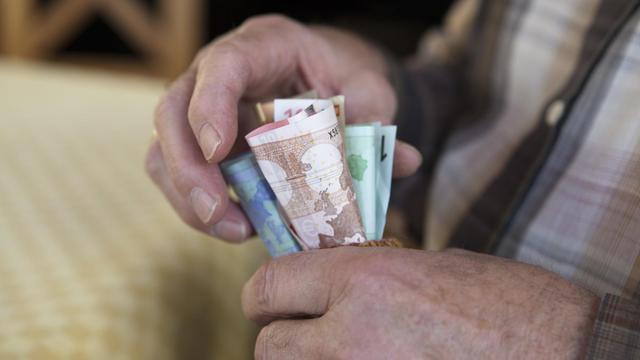 Ein älterer Mann hält mehrere Geldscheine in den Händen (Symbolbild).