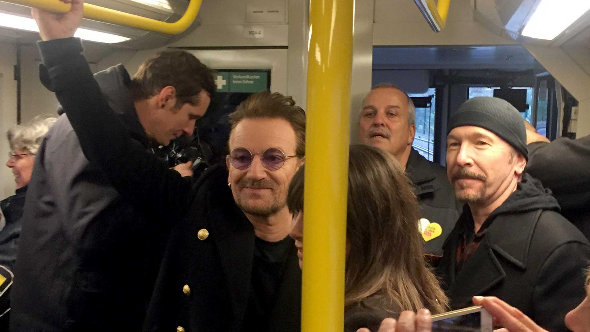 Sänger Bono (l) und der Gitarrist David Howell Evans "The Edge" (r) von der Band U2 stehen am 06.12.2017 in der U-Bahn der Linie U2. Sänger Bono (l) und der Gitarrist David Howell Evans "The Edge" (r) von der Band U2 stehen am 06.12.2017 in der U-Bahn der Linie U2.