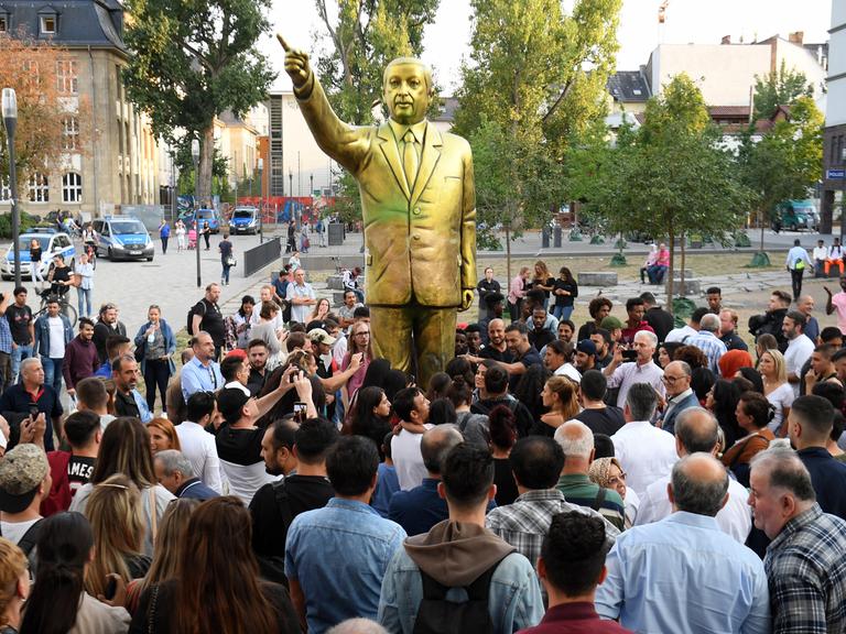 Zahlreiche Menschen haben sich auf dem Platz der Deutschen Einheit vor einer goldenen Erdogan-Statue in Wiesbaden versammelt. Die Statue wurde im Rahmen des Kunstfestivals "Wiesbaden Biennale" aufgestellt.