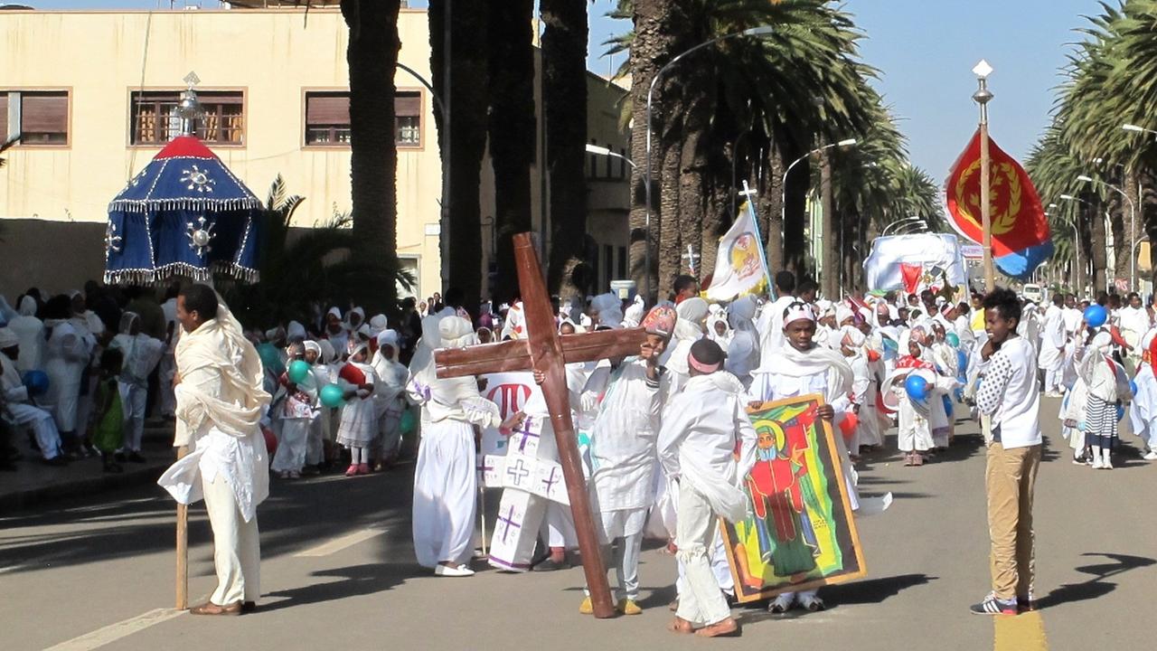 Menschen, die am hohen Feiertag der orthodoxen Kirche in Eritreas Hauptstadt Asmara eine Prozession bilden: mit weißen Gewändern und einem Holzkreuz.