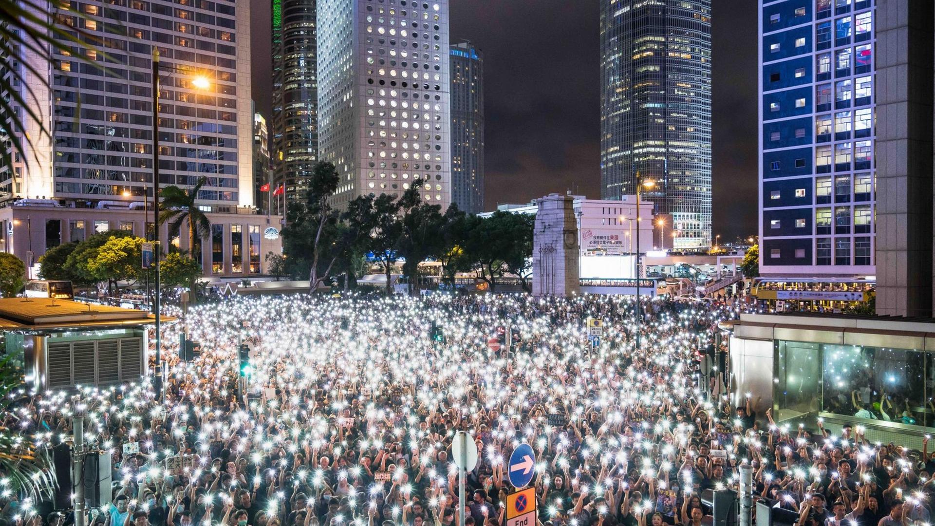 Nächtliche Demonstrantenversammlung mit Smartphones als Taschenlampen, während einer Kundgebung im Chater Garden, am 2. August 2019 in Hong Kong. Im Hintergrund sind beleuchtete Wolkenkratzer zu sehen. Nächtliche Demonstrantenversammlung mit Smartphones als Taschenlampen, während einer Kundgebung im Chater Garden, am 2. August 2019 in Hong Kong. Im Hintergrund sind beleuchtete Wolkenkratzer zu sehen.