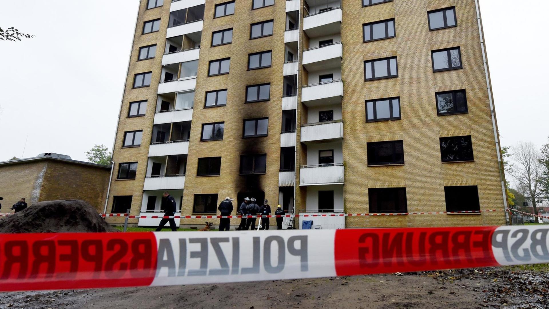 Polizisten stehen am 16.10.2015 in Flensburg vor einer zum Teil ausgebrannten Asylbewerberunterkunft Polizisten stehen am 16.10.2015 in Flensburg vor einer zum Teil ausgebrannten Asylbewerberunterkunft