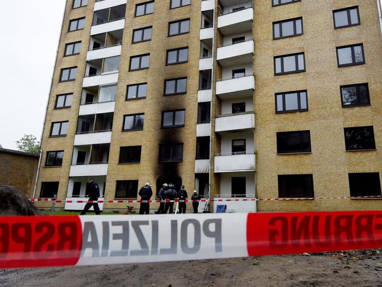 Polizisten stehen am 16.10.2015 in Flensburg vor einer zum Teil ausgebrannten Asylbewerberunterkunft Polizisten stehen am 16.10.2015 in Flensburg vor einer zum Teil ausgebrannten Asylbewerberunterkunft