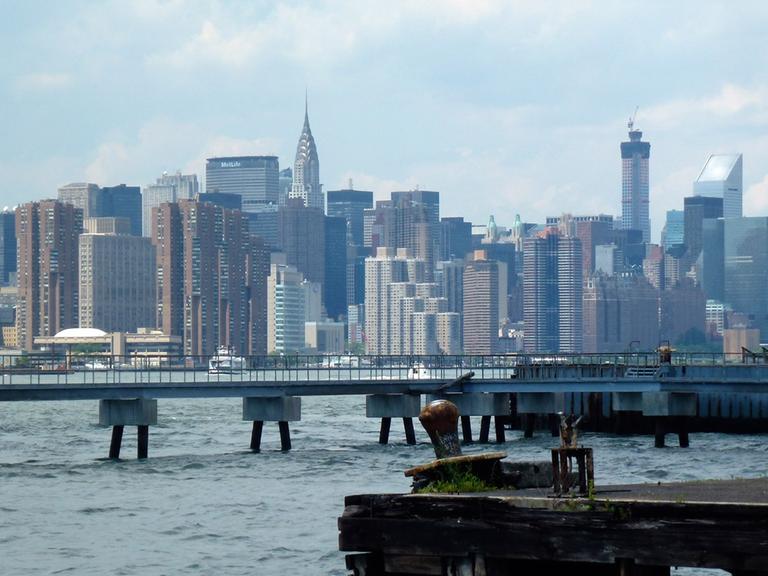 Blick auf den East River mit Manhattan im Hintergrund, aufgenommen vom Ufer in Williamsburg, Brooklyn, New York am 22.06.2014