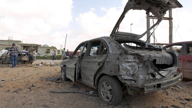 Libyer versammeln sich im März 2014 um ein zerstörtes Auto, nachdem ein bei einem Autobombenanschlag auf eine Militärakademi in Bengasi mindestens fünf Soldaten getötet wurden.
