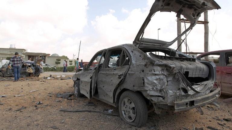 Libyer versammeln sich im März 2014 um ein zerstörtes Auto, nachdem ein bei einem Autobombenanschlag auf eine Militärakademi in Bengasi mindestens fünf Soldaten getötet wurden. Libyer versammeln sich im März 2014 um ein zerstörtes Auto, nachdem ein bei einem Autobombenanschlag auf eine Militärakademi in Bengasi mindestens fünf Soldaten getötet wurden.