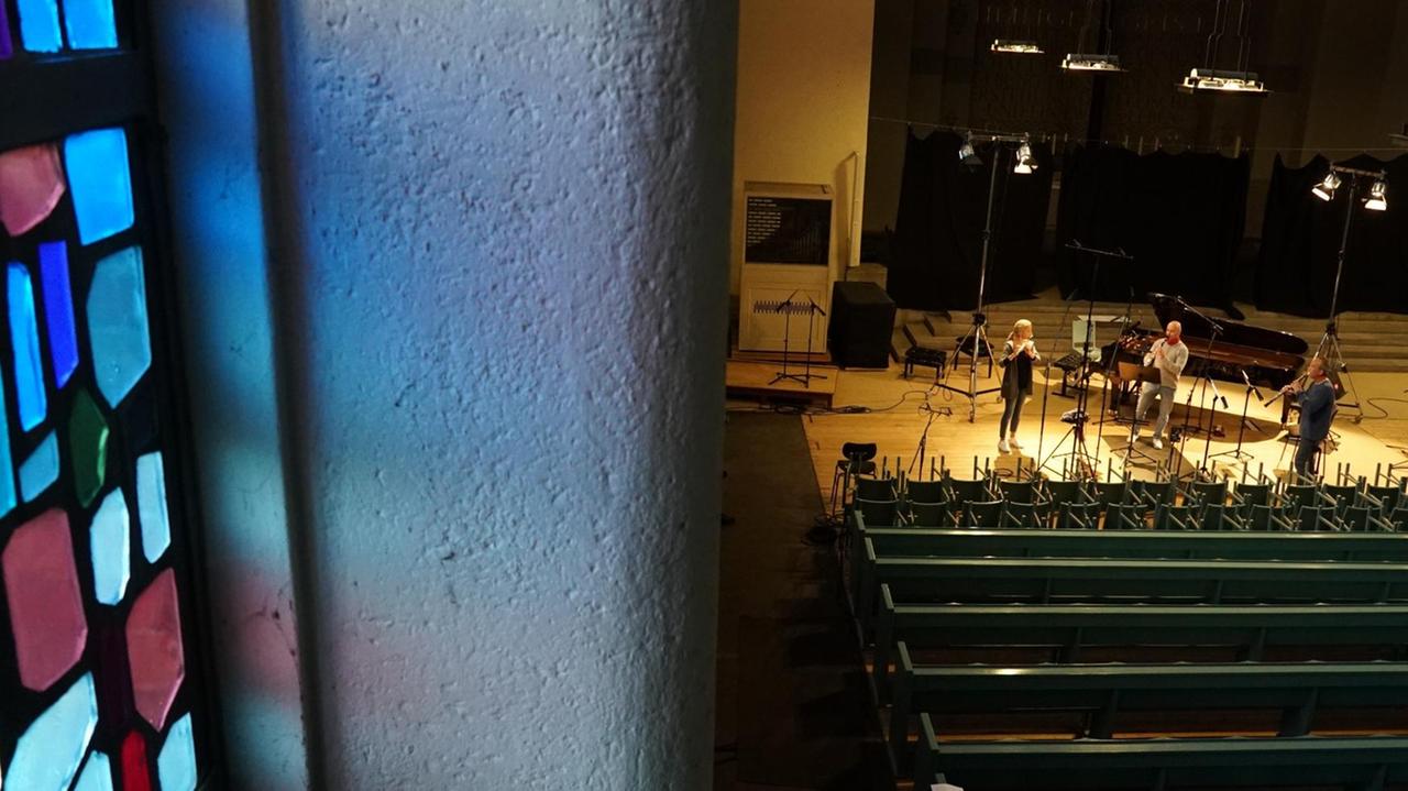 Drei Musiker stehen in der Entfernung und spielen gemeinsam in einer leeren Kirche. Drei Musiker stehen in der Entfernung und spielen gemeinsam in einer leeren Kirche.