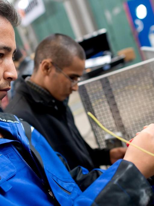 Flüchtlinge arbeiten an einem Werkstück