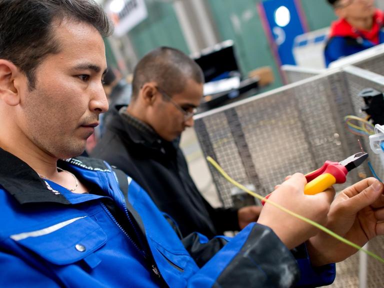 Flüchtlinge arbeiten an einem Werkstück