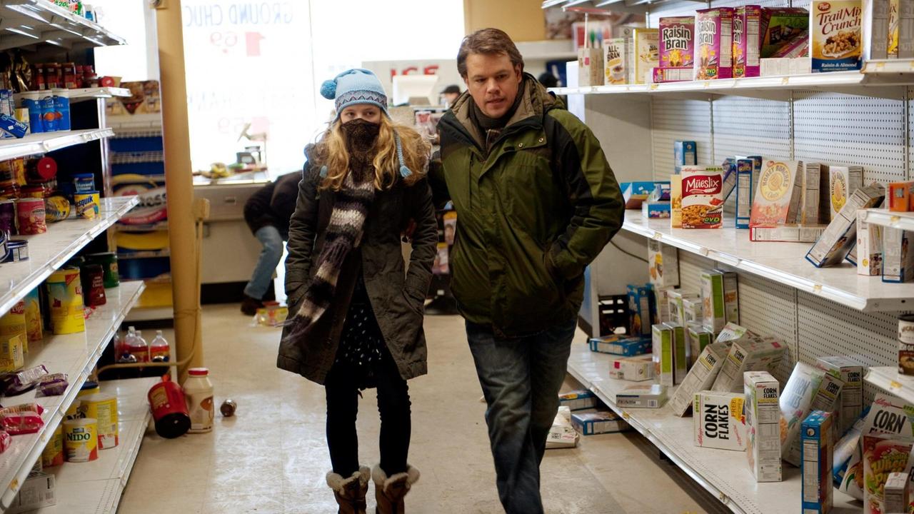 Die Schauspielerin Anna Jacoby-Heron, und der Schauspieler Matt Damon in dem Film "Contagion" von 2011. Eine Frau mit Maske und ein Mann gehen durch einen Supermarkt. Die Schauspielerin Anna Jacoby-Heron, und der Schauspieler Matt Damon in dem Film "Contagion" von 2011. Eine Frau mit Maske und ein Mann gehen durch einen Supermarkt.