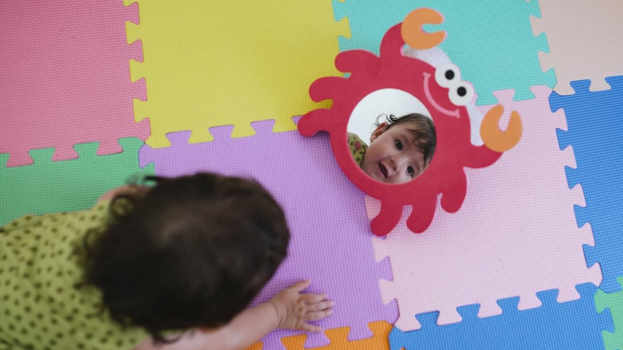 Ein Baby schaut sich im Spielzeugspiegel an Ein Baby schaut sich im Spielzeugspiegel an