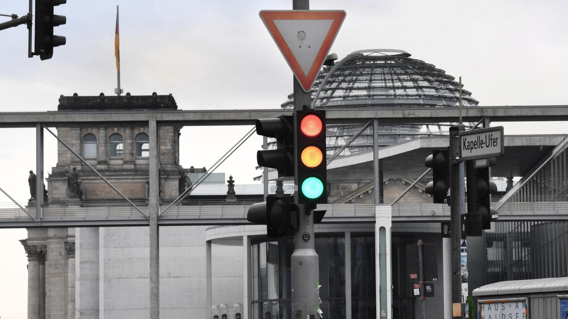 Eine Ampel, an der für einen Moment die Farben Rot, Gelb und Grün gleichzeitig leuchten, ist am Tag nach der Bundestagswahl im Regierungsviertel vor der Kuppel des Reichstagsgebäudes, dem Sitz des Bundestags, zu sehen.