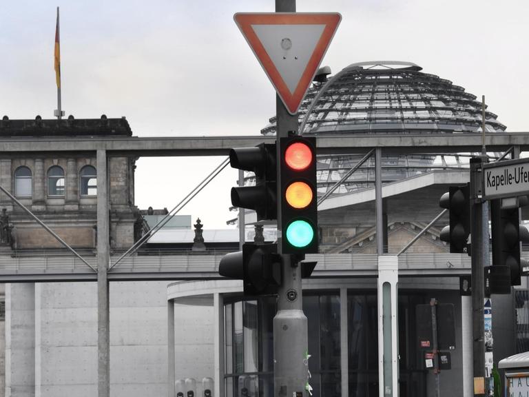 Eine Ampel, an der für einen Moment die Farben Rot, Gelb und Grün gleichzeitig leuchten, ist am Tag nach der Bundestagswahl im Regierungsviertel vor der Kuppel des Reichstagsgebäudes, dem Sitz des Bundestags, zu sehen.