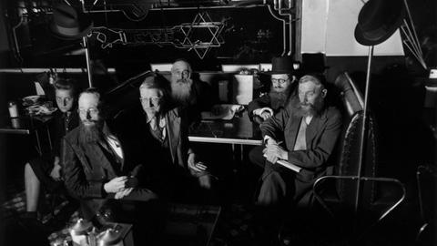 Orthodoxe Juden lauschen in einem jiddischen Café einer Radioübertragung während des Zweiten Weltkriegs.