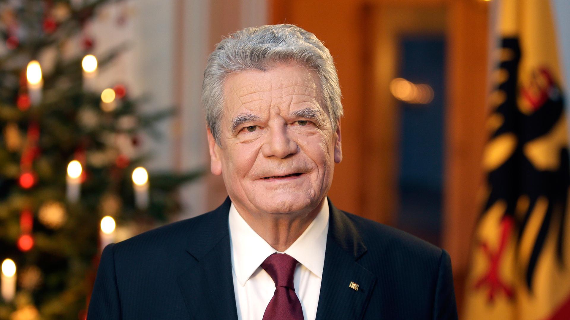 Bundespräsident Gauck nach seiner Weihnachtsansprache, im Hintergrund ein geschmückter Weihnachtsbaum und die deutsche Flagge.
