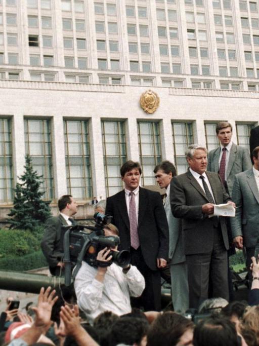 Der russische Präsident Boris Jelzin (M, mit Papier in der Hand), auf einem Panzer vor dem russischen Regierungsgebäude in Moskau stehend, ruft die Bevölkerung am 19. August 1991 zum Generalstreik auf.