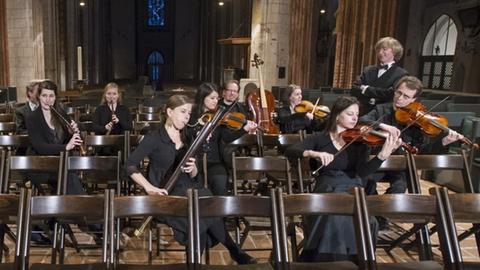 Musiker des Sächsischen Barockorchesters Leipzig sitzen verstreut in einem Kirchenschiff