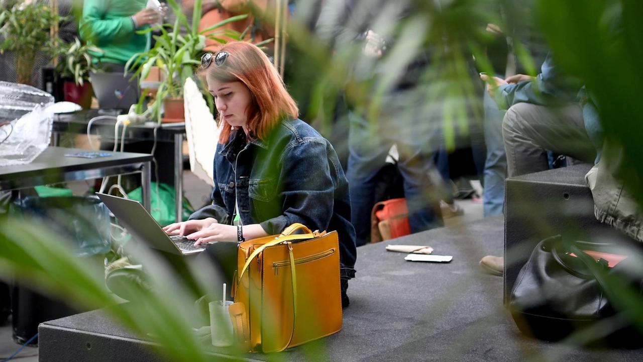 06.05.2019, Berlin: Eine junge Frau sitzt an ihrem Laptop im Community Garden auf dem Gelände Internetkonferenz "re:publica". 06.05.2019, Berlin: Eine junge Frau sitzt an ihrem Laptop im Community Garden auf dem Gelände Internetkonferenz "re:publica".