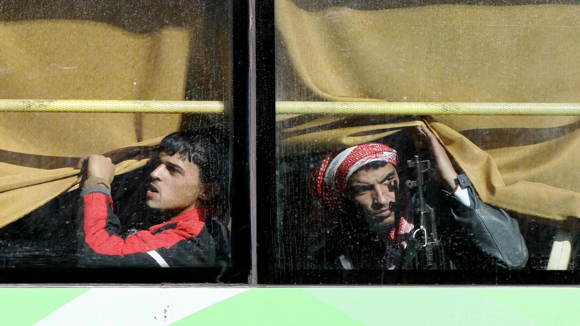 Kämpfer der syrischen Rebellen in einem Bus, der sie aus der Stadt Homs bringt. Kämpfer der syrischen Rebellen in einem Bus, der sie aus der Stadt Homs bringt.