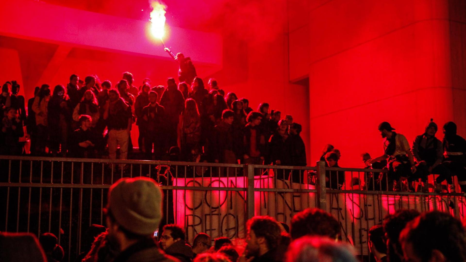 Ein Student brennt in einem Pulk Menschen eine Fackel ab. Das Foto ist ganz in rot getaucht. Ein Student brennt in einem Pulk Menschen eine Fackel ab. Das Foto ist ganz in rot getaucht.