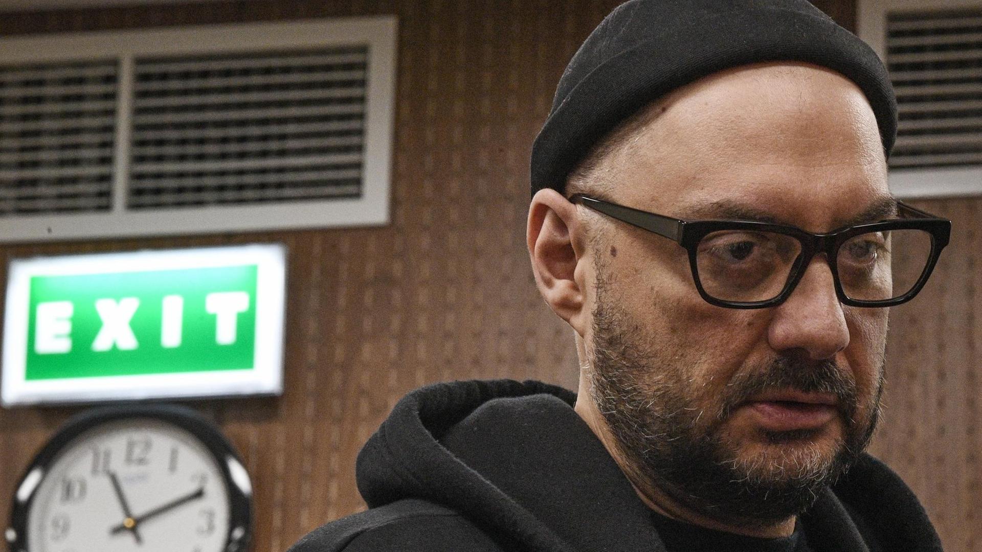 Regisseur Kirill Serebrennikow im Gerichtssaal. Im Hintergrund ist eine Wanduhr und ein grünes Fluchtschild mit der Aufschrift "exit" zu sehen. Regisseur Kirill Serebrennikow im Gerichtssaal. Im Hintergrund ist eine Wanduhr und ein grünes Fluchtschild mit der Aufschrift "exit" zu sehen.