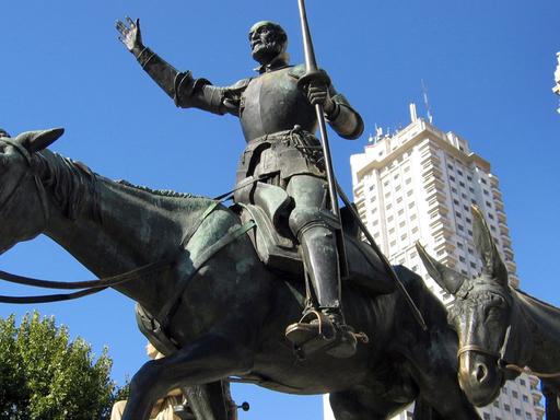 Skulpturen der Cervantes-Romanfiguren Don Quijote und Sancho Panza vor dem Torre de Madrid (Hintergrund) an der Plaza Espana in Madrid.