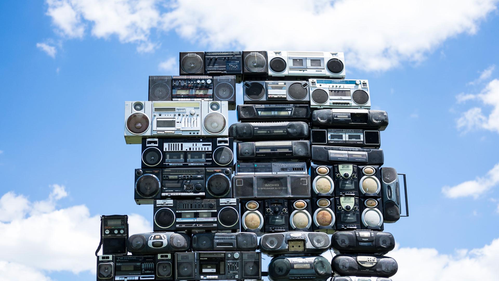 Aufeinander gestapelte Radios mit einem blauen Himmel und weißen Wolken im Hintergrund. Aufeinander gestapelte Radios mit einem blauen Himmel und weißen Wolken im Hintergrund.