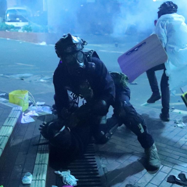 Ein Polizist mit Maske hält einen Demonstranten außerhalb der Hong Kong Polytechnic Universität fest, während es am frühen Montag am Campus zu schweren Zusammenstößen mit den Demonstranten kam. 