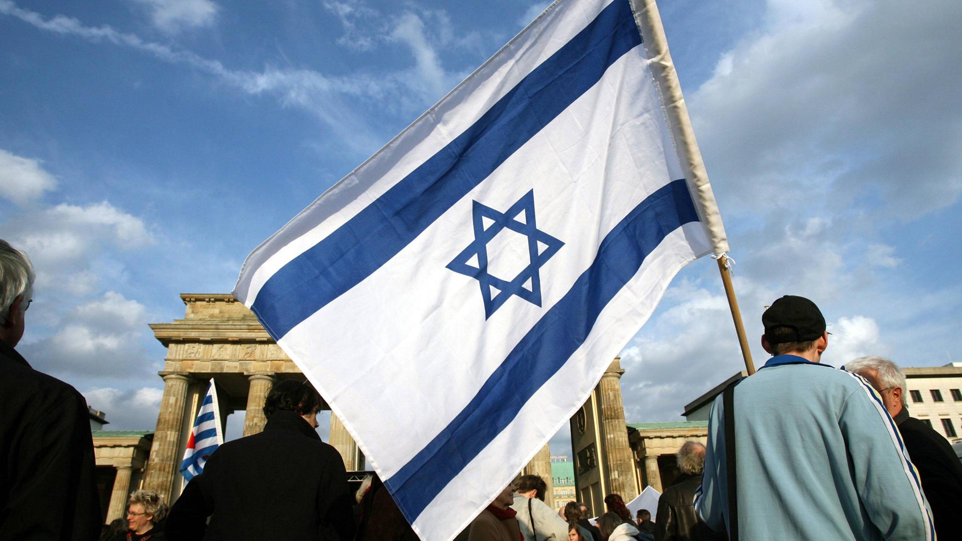 Ein Mann mit einer israelischen Fahne steht in Berlin am Brandenburger Tor. Ein Mann mit einer israelischen Fahne steht in Berlin am Brandenburger Tor.