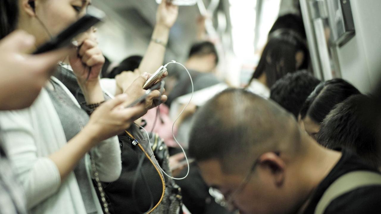 Fahrgäste in einer U-Bahn benutzen ihre Smartphones.