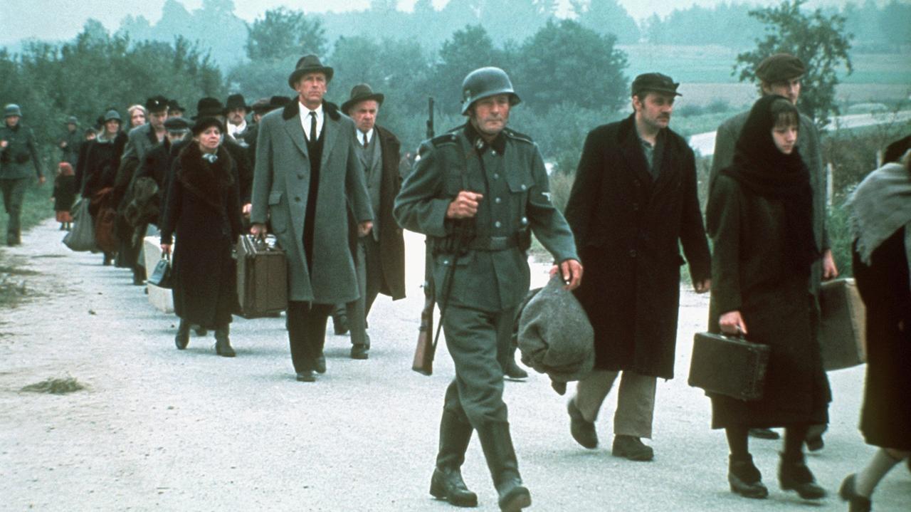 Das Bild zeigt eine Szene aus der US-amerikanischen Fernsehserie "Holocaust", in der deportierte Juden auf dem Weg ins Konzentrationslager durch den Schnee gehen. Das Bild zeigt eine Szene aus der US-amerikanischen Fernsehserie "Holocaust", in der deportierte Juden auf dem Weg ins Konzentrationslager durch den Schnee gehen.