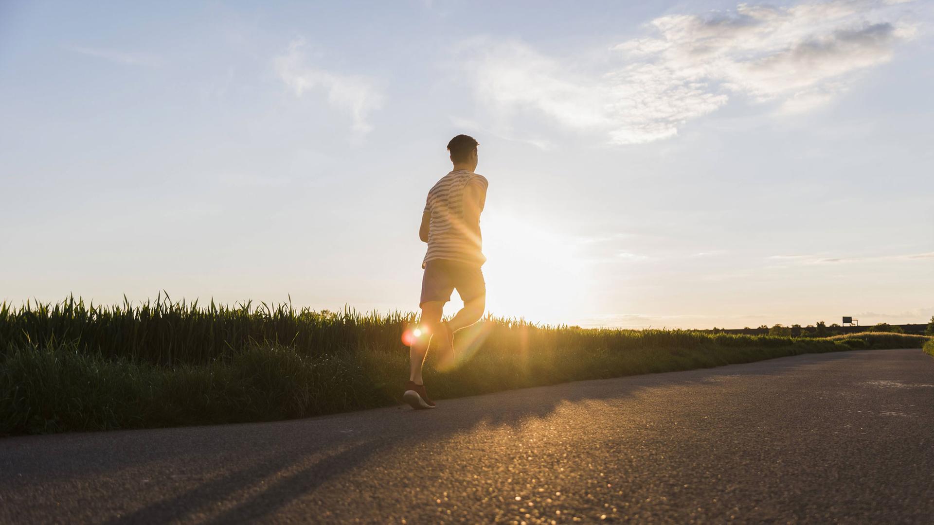 Ein Jogger läuft im Sonnenuntergang Ein Jogger läuft im Sonnenuntergang