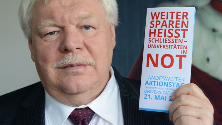Horst Hippler hält ein Faltblatt mit der Aufschrift "Weiter sparen heißt schließen - Universitäten in Not" hoch. Horst Hippler hält ein Faltblatt mit der Aufschrift "Weiter sparen heißt schließen - Universitäten in Not" hoch.