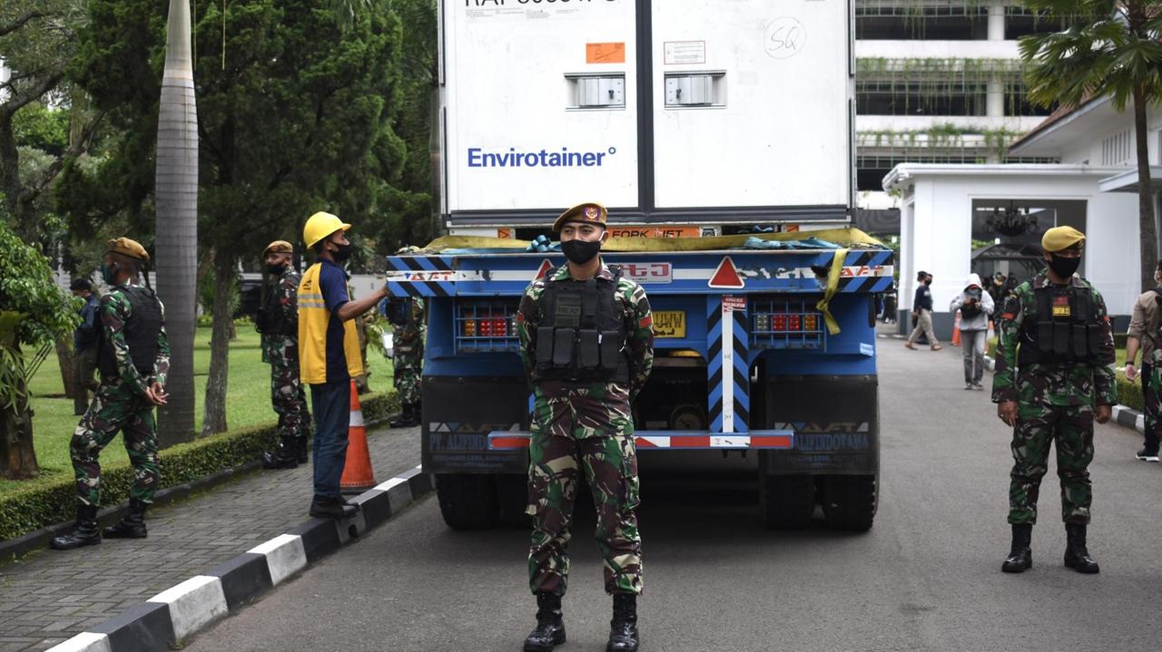 Bewaffnete Sicherheitskräfte vor einem Kühlcontainer mit zehn Millionen Dosen des Covid-19-Impfstoffes Sinovac bei der Ankunft in der Fabrik von Bio Farma in Bandung, Indonesien on February 2, 2021.
