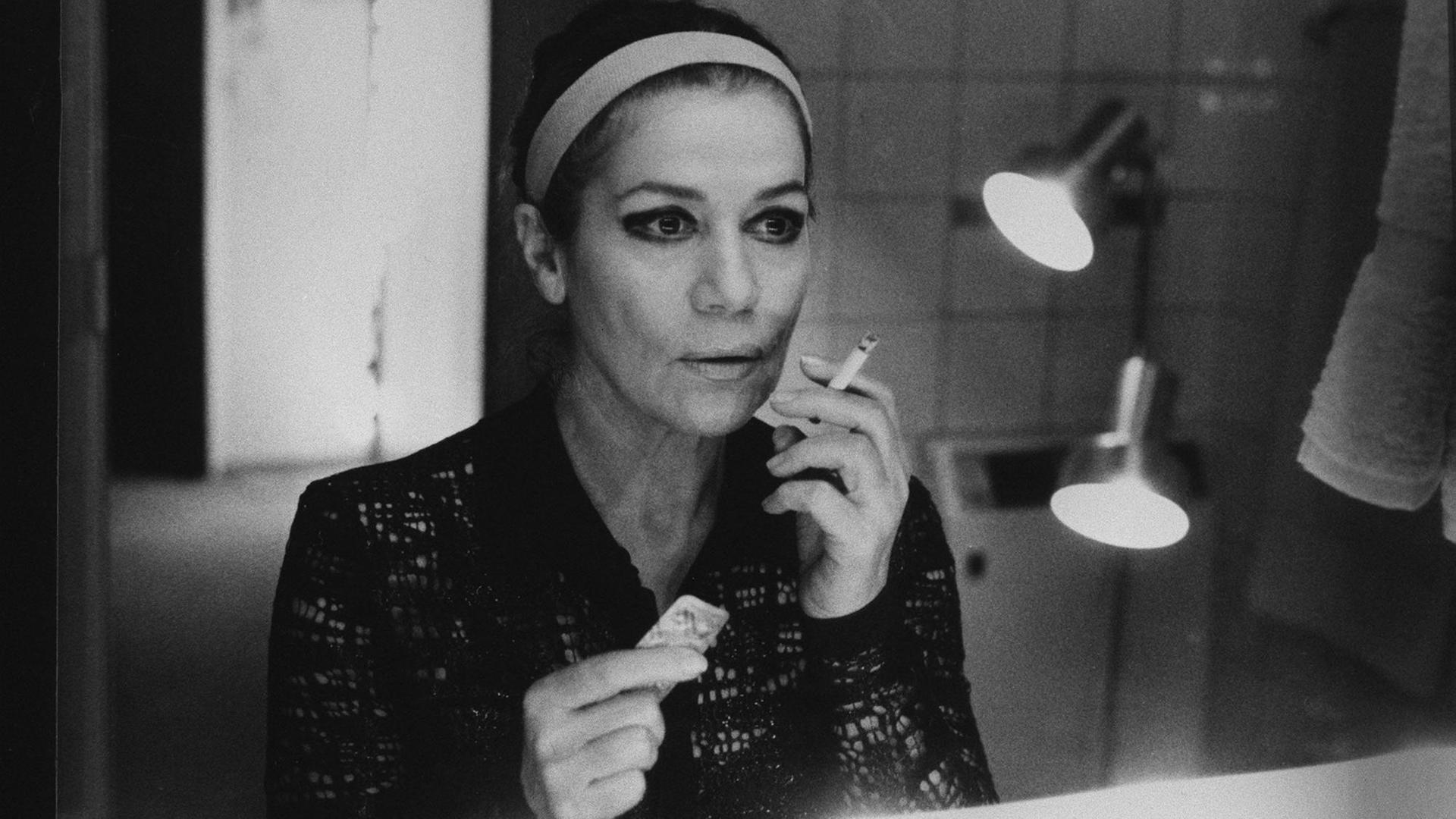 Hannelore Elsner hält in einer Hand eine Zigarette, in der anderen einen Streifen Tabletten. Sie schaut in den Spiegel. Hannelore Elsner hält in einer Hand eine Zigarette, in der anderen einen Streifen Tabletten. Sie schaut in den Spiegel.