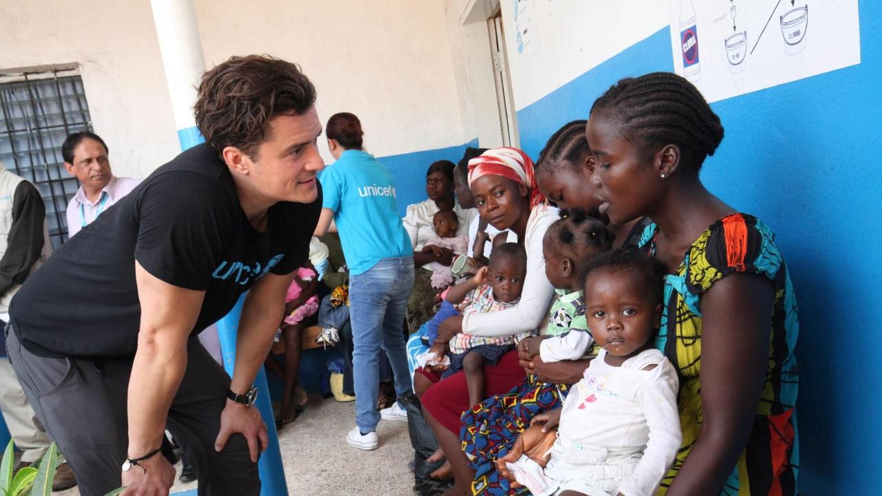 Liberia, 23 März 2015: Der britische Schauspieler und Unicef-Botschafter Orlando Bloom spricht mit einer Mutter und ihrem Kind vor einer Klinik. Liberia, 23 März 2015: Der britische Schauspieler und Unicef-Botschafter Orlando Bloom spricht mit einer Mutter und ihrem Kind vor einer Klinik.
