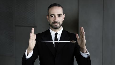 Der Dirigent Antonello Manacorda, ein Dirigierstab scheint zwischen seinen Händen zu schweben
