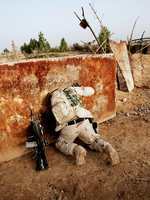 Ein US-Soldat sucht Waffen in einem ehemaligen Wassertank im Jahr 2005 im Irak - er ist von hinten zu sehen und steckt bis zu den Schultern in der Öffnung: Foto aus dem Bildband "hello camel" von Christoph Bangert über die Absurdität von Krieg