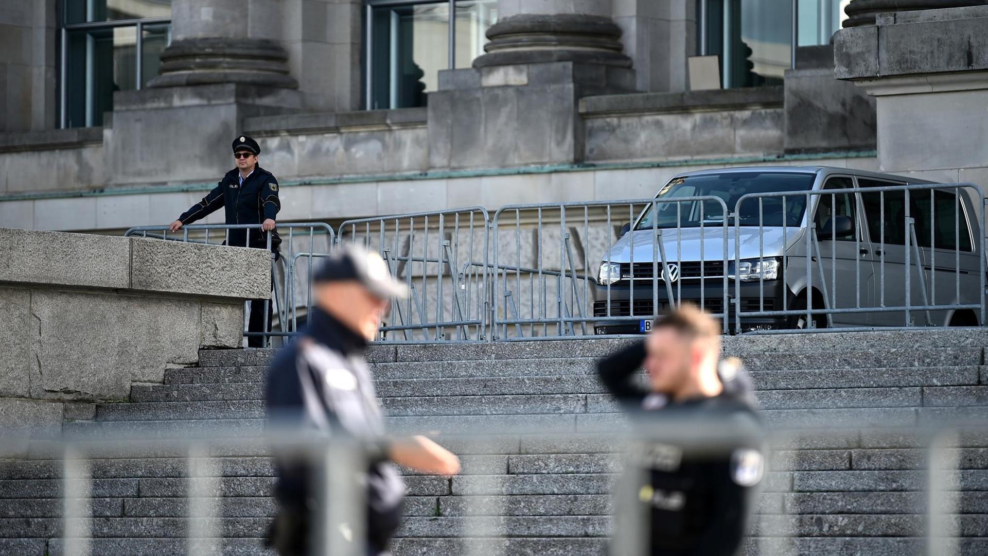 Drei Polizisten stehen mit Absperrgittern vor dem Reichstagsgebäude in Berlin. Drei Polizisten stehen mit Absperrgittern vor dem Reichstagsgebäude in Berlin.