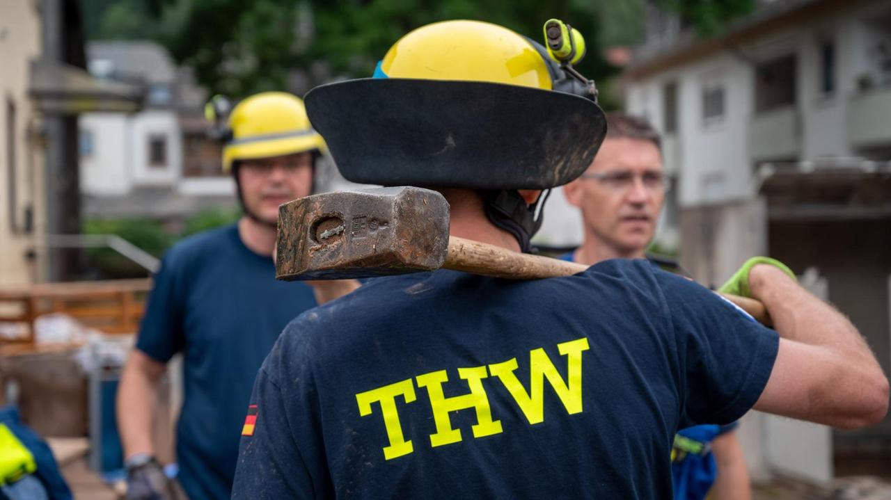 Ein THW-Helfer steht mit einem Vorschlaghammer im Trierer Stadtteil Ehrang, um bei den Aufräumarbeiten nach dem Hochwasser der Kyll zu helfen. Zahlreiche Häuser im Ort waren betroffen, Bewohner mussten evakuiert werden. Aufnahme vom 17.07.2021.
