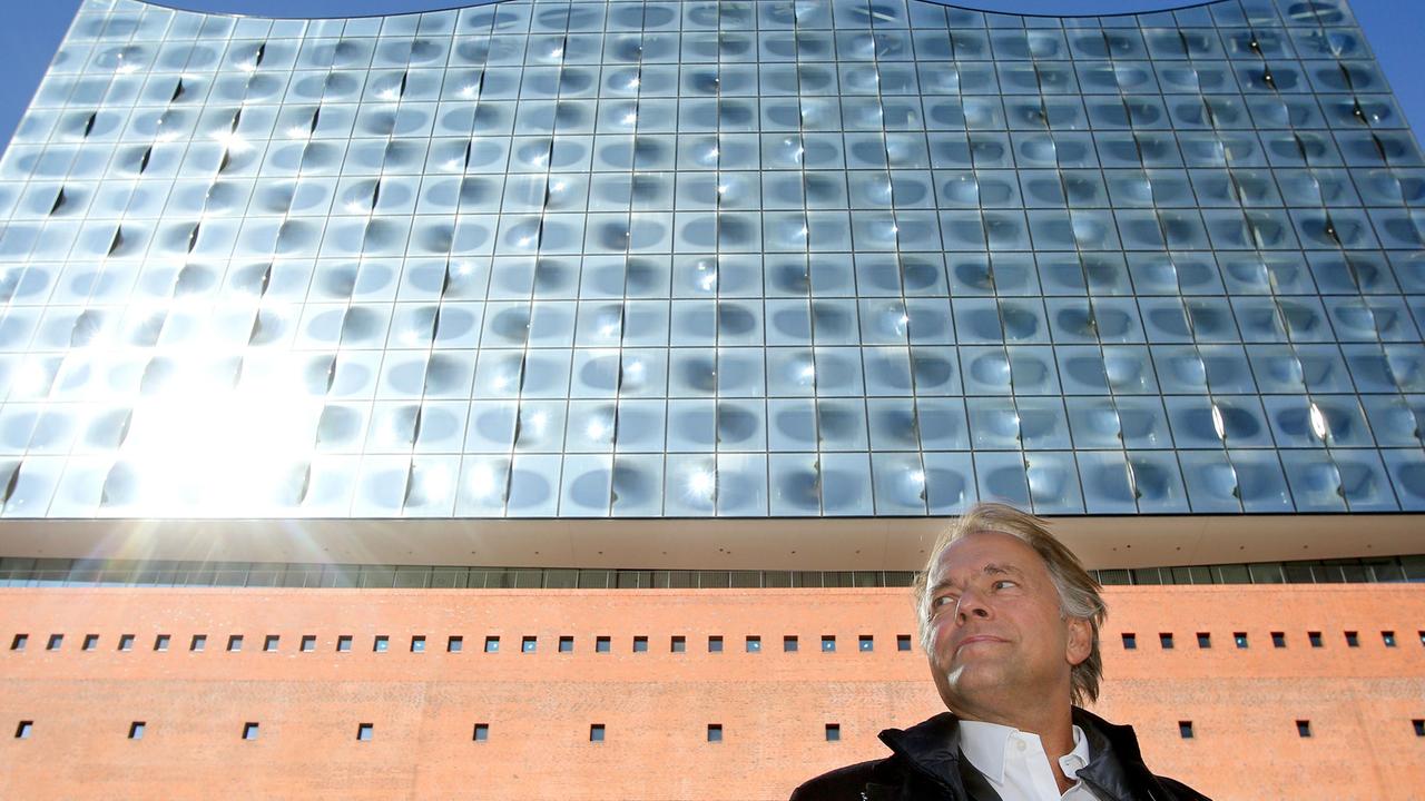 Der Dirigent Thomas Hengelbrock vor der hell-glänzenden Fassade der hohen Hamburger Elbphilharmonie. Der Dirigent Thomas Hengelbrock vor der hell-glänzenden Fassade der hohen Hamburger Elbphilharmonie.
