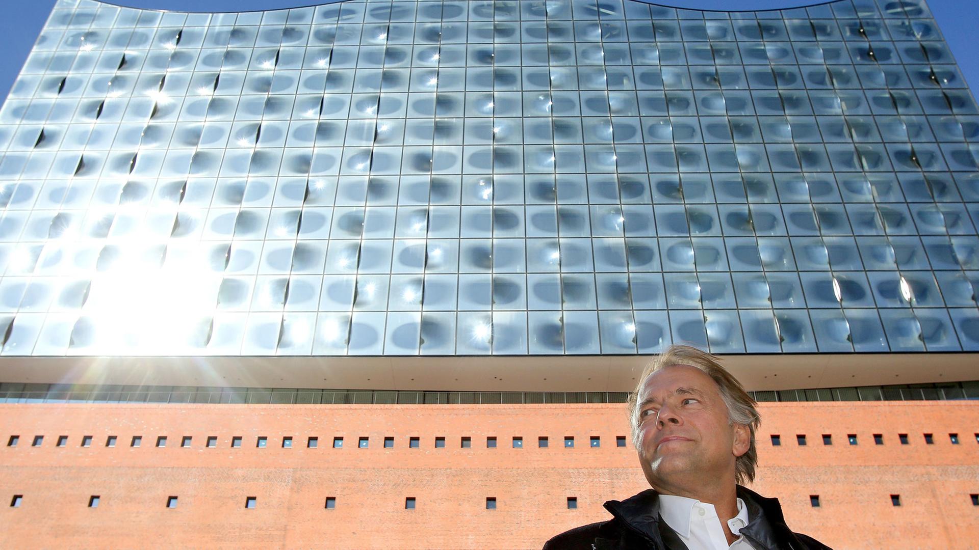 Der Dirigent Thomas Hengelbrock vor der hell-glänzenden Fassade der hohen Hamburger Elbphilharmonie. Der Dirigent Thomas Hengelbrock vor der hell-glänzenden Fassade der hohen Hamburger Elbphilharmonie.