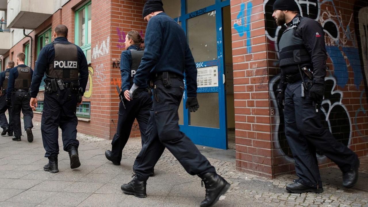 Einsatzkräfte der Polizei gehen am 12.04.2016 vor einem Wohnhaus in Berlin im Bezirk Neukölln. Am frühen Morgen gab es hier Hausdurchsuchungen und Festnahmen. Mit einem Großeinsatz, an dem auch Kräfte des Spezialeinsatzkommandos beteiligt sind, geht die Polizei gegen eine mutmaßlich kriminelle arabische Großfamilie vor. 