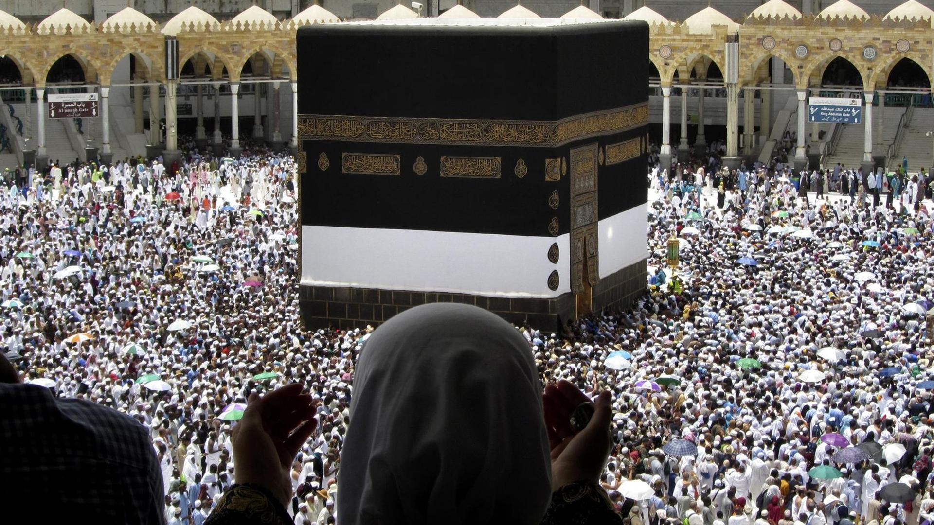 Eine muslimische Pilgerin betet, während sie zuschaut, wie Tausende von Pilgern um die Kaaba herumgehen, das kubische Gebäude an der Großen Moschee, vor der Hadsch-Pilgerfahrt in der muslimischen heiligen Stadt Mekka. Eine muslimische Pilgerin betet, während sie zuschaut, wie Tausende von Pilgern um die Kaaba herumgehen, das kubische Gebäude an der Großen Moschee, vor der Hadsch-Pilgerfahrt in der muslimischen heiligen Stadt Mekka.