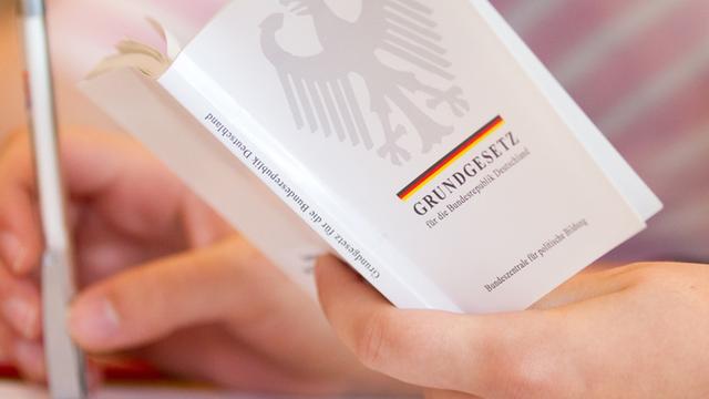 Eine Jura-Studentin hält in einer Vorlesung an der Universität Osnabrück (Niedersachsen) eine Ausgabe vom Grundgesetz in der Hand.